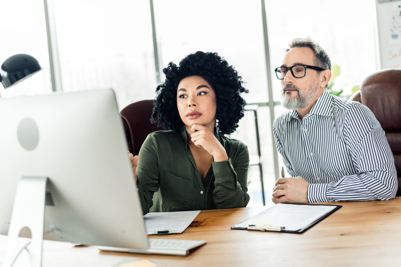 colleagues-discussing-computer-screen-office
