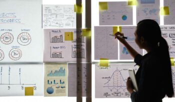 woman-presenting-project-progress-and-charts-on-glass-board